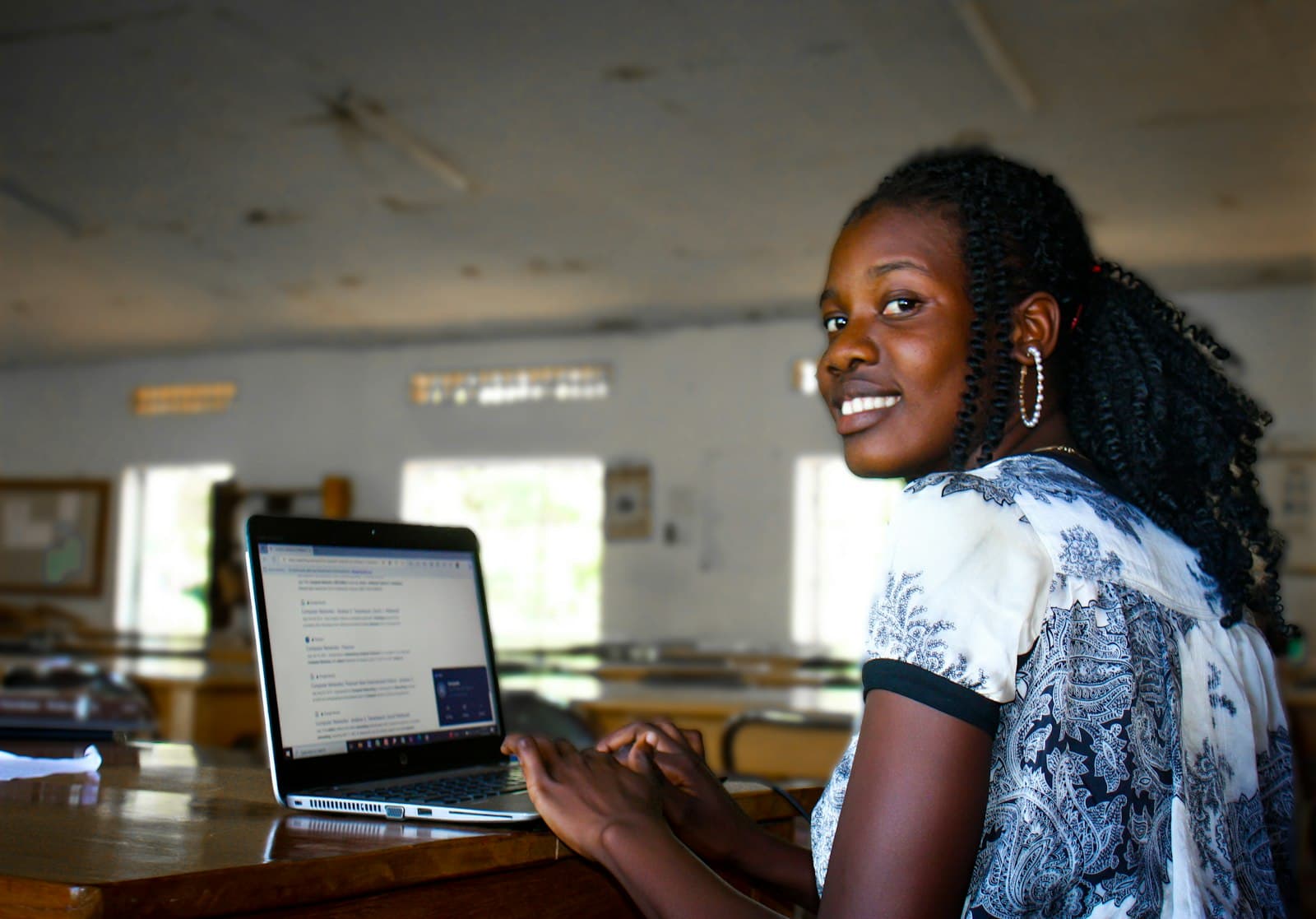 Student smiling at the camera while working on a laptop