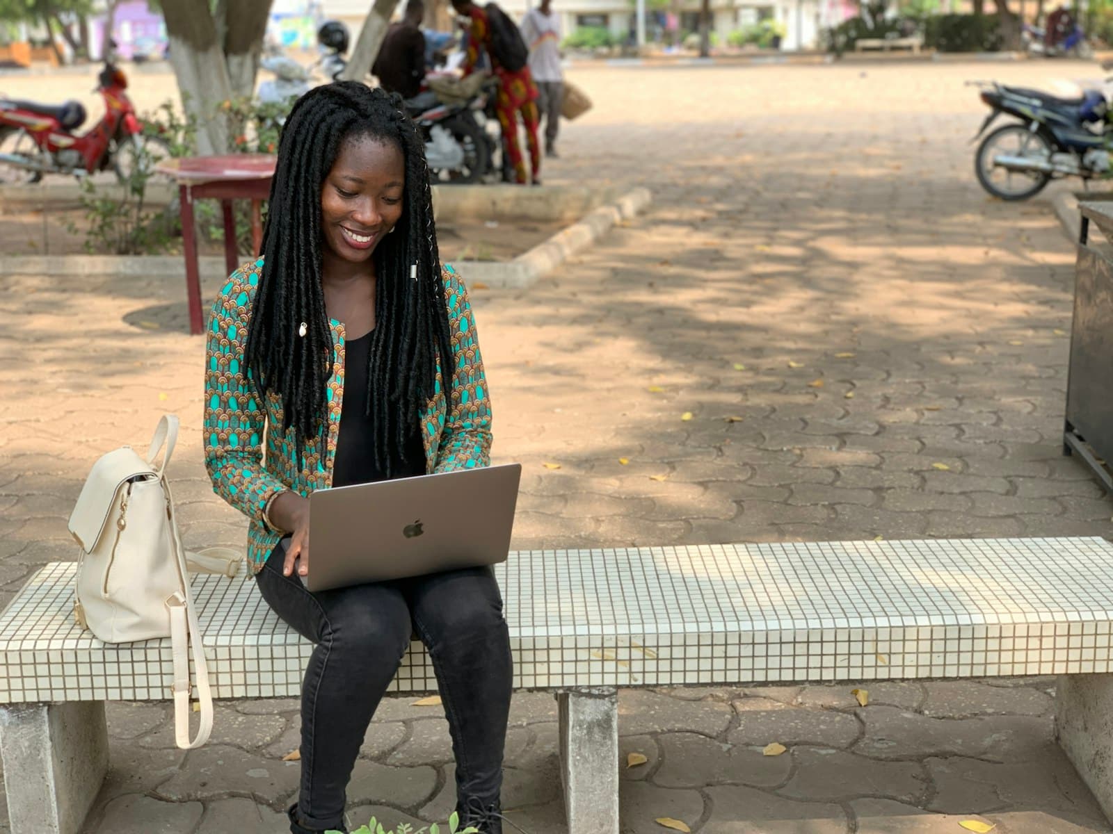 Student smiling while working on a laptop outdoors on campus